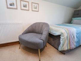 A bedroom with a bed and armchair at Chestnut Barn Aislaby near Whitby