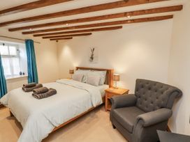 A bedroom with a bed and armchair at Chestnut Barn Aislaby near Whitby
