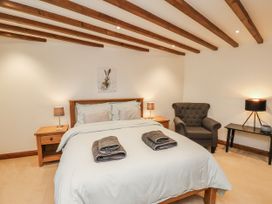 A bedroom with a bed and an armchair at Chestnut Barn Aislaby near Whitby