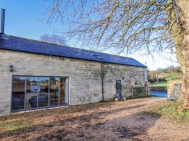 An outdoor view of a building with a stone wall and a tree at Chestnut Barn Aislaby near Whitby