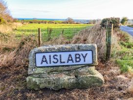 A sign for Aislaby in a field near a road in Aislaby near Whitby