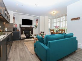 A living room with kitchen, sofa, table and chairs at The Magnolia in Rhos-On-Sea