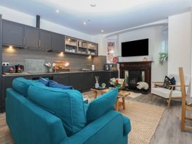 A living room with a sofa and kitchen area at The Magnolia in Rhos-On-Sea