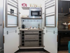 A kitchen with storage cabinets and microwave at The Magnolia in Rhos-On-Sea
