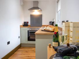 A kitchen with a bottle of champagne and bread at Beech Cottages in Llanrwst