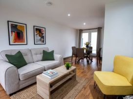 A living room with a sofa a coffee table and a dining area at Beech Cottages Llanrwst