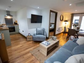 A living room with sofa and kitchen area at Beech Cottages Llanrwst