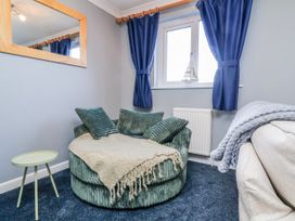 A snug area with an armchair and side table at Sea Spray in Westward Ho!