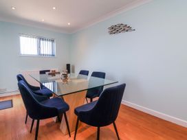 A dining room with a glass table and blue chairs at Sea Spray in Westward Ho!