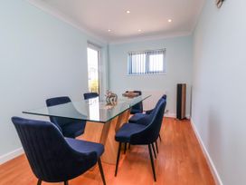 A dining room with a glass table and blue chairs at Sea Spray in Westward Ho!