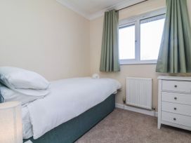 A bedroom with a bed and nightstand at Sea Spray in Westward Ho!