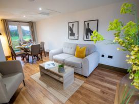 A living room with a sofa and dining area at Fir Cottages in Llanrwst