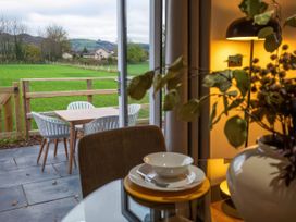 A dining area with a table and chairs overlooking a field at Fir Cottages in Llanrwst