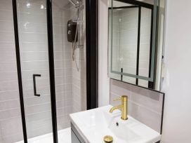 A bathroom with a shower enclosure and a sink at Silver Birch Cottage Llanrwst