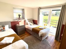 A bedroom with two beds and a door leading outside at River View Cottage Llanrwst