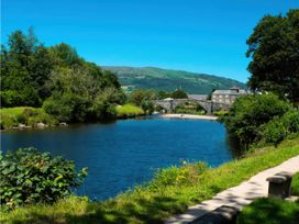 A view of a river with a bridge and trees at Mountain View Cottage in Llanrwst