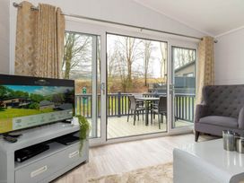 A living room with a sofa and TV leading to a deck at The Falls in Leyburn