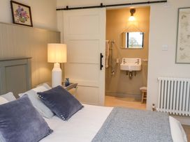 A bedroom featuring a bed, lamp, and a bathroom area with a sink at Fairview in Darsham