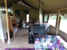 An indoor camping area with a wood stove and shelves at Aeron in Newcastle Emlyn