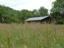A building in a field with trees and grass at Aeron in Newcastle Emlyn