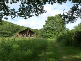 A tent near a grassy path surrounded by trees at Teifi in Newcastle Emlyn