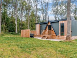 A house with a deck and hot tub surrounded by trees at Tennyson Spa in Louth