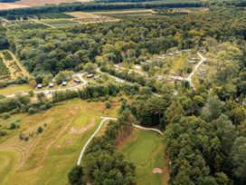 A view of cabins and a golf course surrounded by trees at Somersby Spa (Pet) in Louth