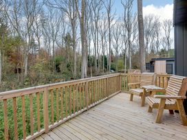 A deck area with wooden chairs overlooking trees at Tennyson Spa (Pet) in Louth