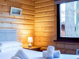 A bedroom with wooden walls and a lamp at Maple Lodge in Louth
