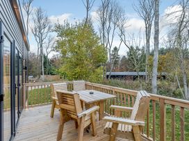 A deck with wooden furniture and trees at Anderby Spa (Pet) in Louth