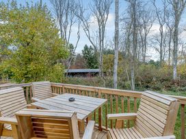 A wooden deck with chairs and a table overlooking trees at Anderby Spa (Pet) Louth