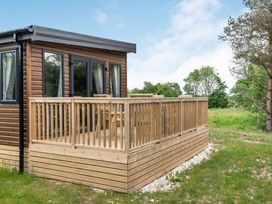A wooden deck with a cabin surrounded by grass and trees at Caistor Spa in Louth