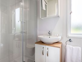 A bathroom with a shower, sink, and mirror at Caistor Spa in Louth