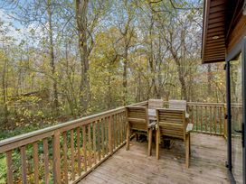 A deck with a wooden table and chairs surrounded by trees at Alford Spa in Louth