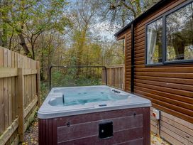 A hot tub next to a wooden cabin in a forest at Alford Spa in Louth