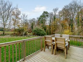 An outdoor deck with wooden chairs and a table at The Kinder Spa (Pet) Louth