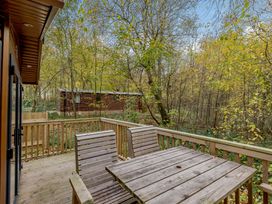 A deck area with a table and chairs overlooking trees at Alford Spa (Pet) in Louth