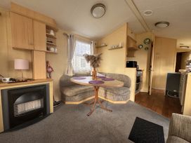 A dining area with seating arrangements and kitchen appliances at 29 Laburnham Court in Fleetwood