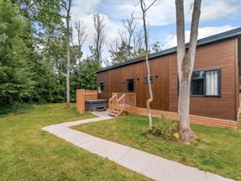 A house with a hot tub and path surrounded by trees at Stamford Spa in Louth