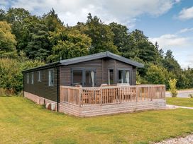 A cabin with a deck surrounded by grass at Elsham Lodge (Pet) Louth