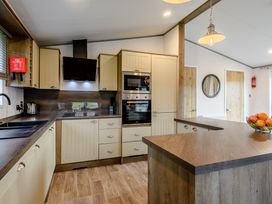 A kitchen with cabinets, stove, sink, and a fruit bowl at Elsham Lodge (Pet) in Louth