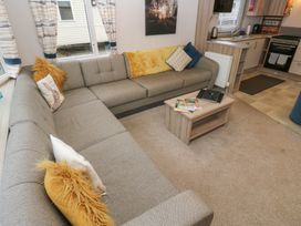 A living room with a sofa coffee table and kitchenette at Woodland View