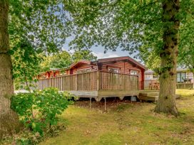 A lodge with a deck surrounded by trees at Hazel Lodge in Louth