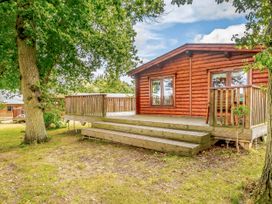 A wooden cabin with a deck and steps at Hazel Lodge in Louth