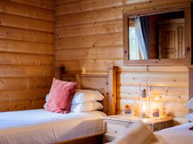 A bedroom with two beds and a lamp on a nightstand at Hazel Lodge in Louth