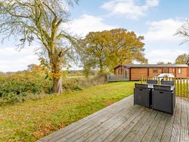 A deck with chairs and trees at Hazel Lodge in Louth