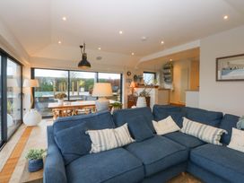 A living room with a sofa and dining area at Bryn Mor Cottage in Mynytho near Llanbedrog