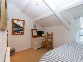 A bedroom with a chair and a dresser at Bryn Mor Cottage, Mynytho near Llanbedrog
