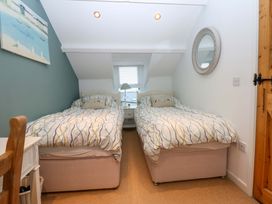 A bedroom with two single beds and a bedside table at Bryn Mor Cottage in Mynytho near Llanbedrog