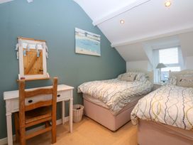 A bedroom with two beds and a desk at Bryn Mor Cottage Mynytho near Llanbedrog
